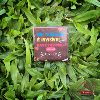 Chocolate com embalagem castanha e texto colorido sobre folhas verdes.