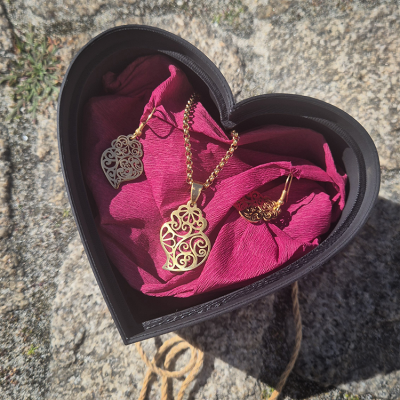 Conjunto de joias em forma de coração numa caixa preta em formato de coração com tecido rosa