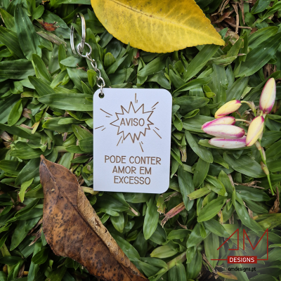 Chaveiro branco com texto sobre folhas verdes e folhas secas