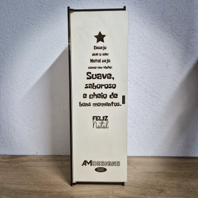 Caixa de madeira clara com texto gravado de Natal e logotipo AMDESIGNS 2023