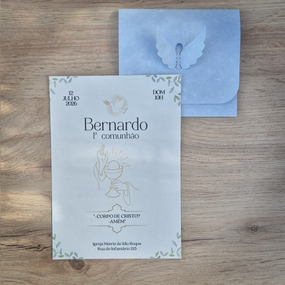 Convite para 1ª comunhão com envelope azul decorado, sobre mesa de madeira