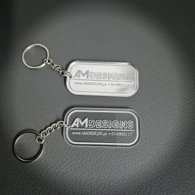 Dois porta-chaves transparentes com texto cinzento AMDESIGNS e contacto, em fundo preto