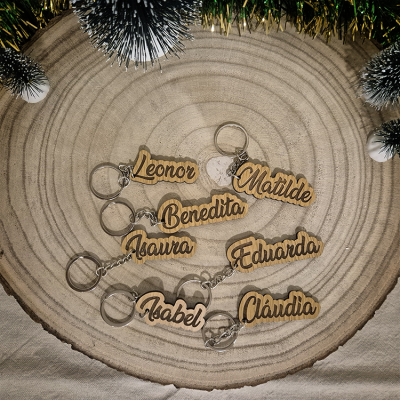 Porta-chaves de madeira com nomes gravados em letras cursivas, numa base de madeira circular com decoração de pinheiro e franjas douradas