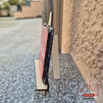 Placa de pedra vermelha em suporte de madeira sobre mesa de pedra cinzenta ao ar livre