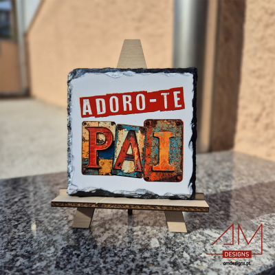 Placa decorativa quadrada em pedra com o texto ADORO-TE PAI em várias cores sobre cavalete de madeira.