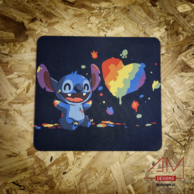 Mousepad preto com personagem azul e coração colorido em padrões de arco-íris sobre superfície de madeira reciclada