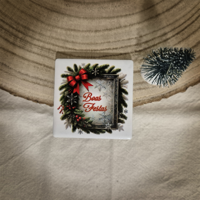 Azulejo natalício branco com ramos de pinheiro e texto Boas Festas