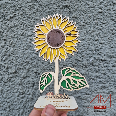 Estatueta de girassol em madeira com nome gravado, fundo de parede cinzenta