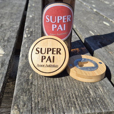 Abridor de garrafas de madeira redondo com gravação SUPER PAI Amor Autêntico sobre mesa de madeira com garrafa atrás.