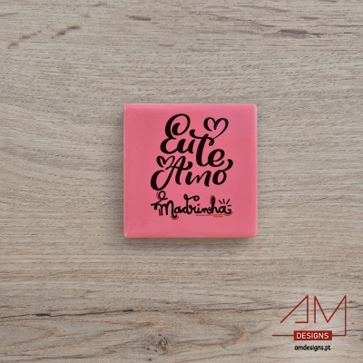 Quadrado rosa com texto 'Eu te Amo Madrinha' em caligrafia preta sobre madeira clara.