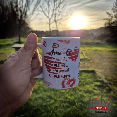 Caneca branca com corações vermelhos e texto em português segurada ao ar livre durante o pôr do sol.