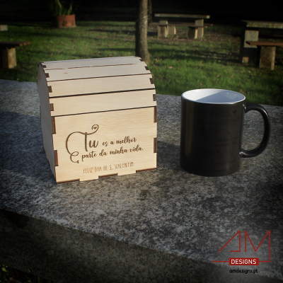 Caixa de madeira gravada a laser com mensagem de São Valentim ao lado de caneca preta sobre banco de pedra