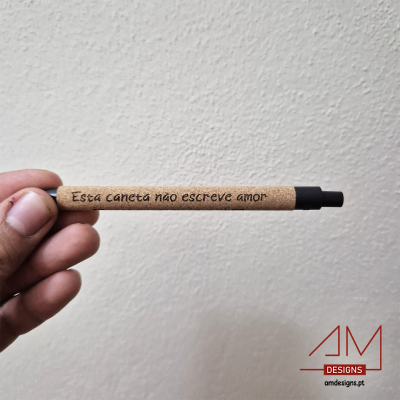 Caneta esferográfica com corpo em cortiça e texto gravado segurada por uma mão