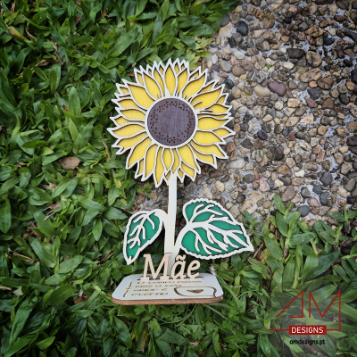 Decoração de girassol em madeira em relva ao lado de caminho de pedras.