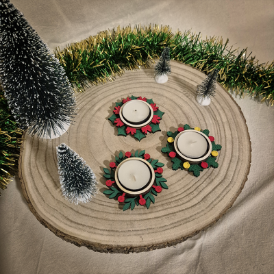 Castiçais de vela tealight natalícios sobre base de madeira com árvores decorativas e guirlanda verde e dourada