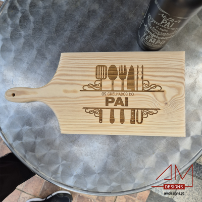 Tábua de madeira gravada com utensílios de cozinha e texto sobre mesa metálica prateada