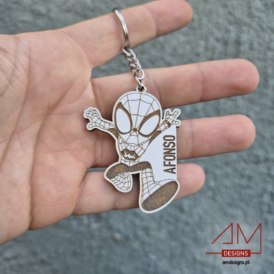 Chaveiro Spider-Man branco e castanho com nome Afonso, segurado à mão, fundo cinzento.