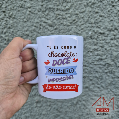 Caneca branca com texto colorido segurada por mão com parede cinza ao fundo