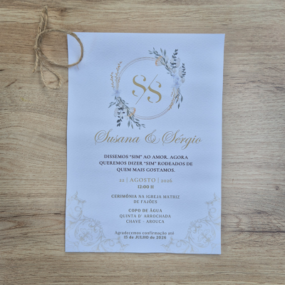Convite de casamento em papel branco com decoração floral e texto em dourado e preto