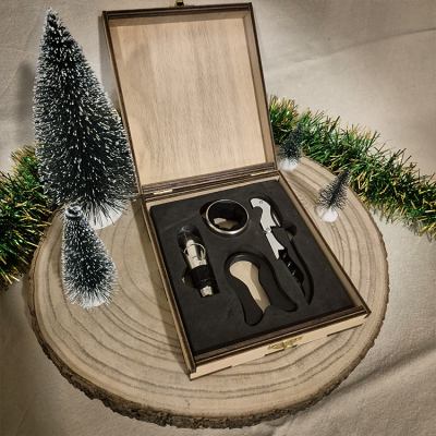 Conjunto de acessórios para vinho em caixa de madeira aberta sobre base de madeira com decoração natalícia.