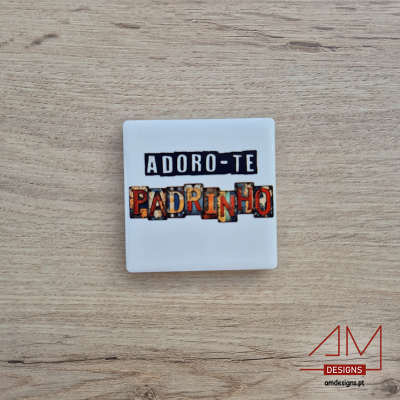 Quadrado de cerâmica branco com texto colorido e logótipo sobre superfície de madeira