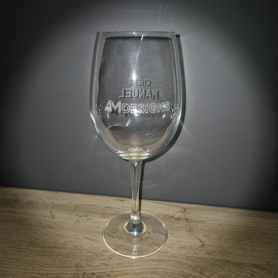 Copo de vinho de vidro transparente com gravura invertida em pés sobre superfície de madeira