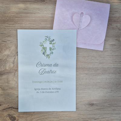 Convite de papel branco com cruz e folhas verdes e envelope rosa com fecho de coração