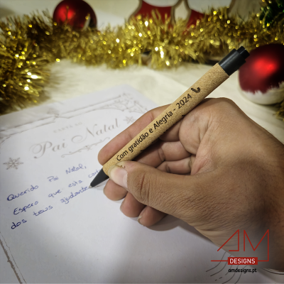 Mão segurando caneta gravada escrevendo carta de Natal com decoração festiva ao fundo