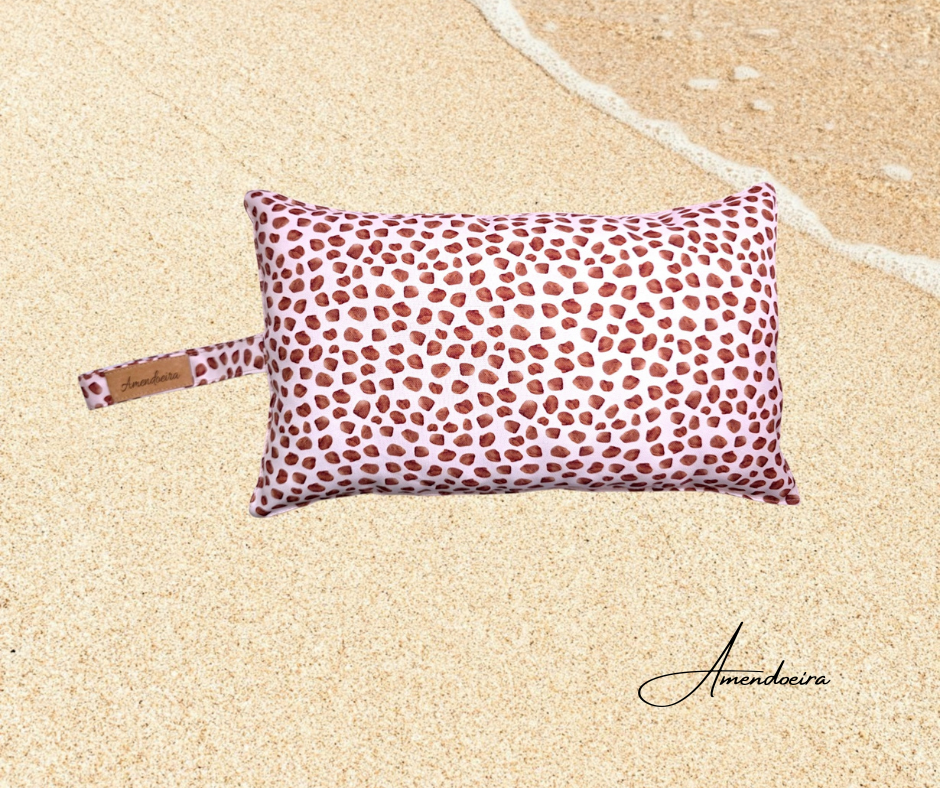 Almofada de praia/piscina - Manchas castanhas Almofada retangular com padrão de pintas castanhas e etiqueta Amendoeira numa superfície de areia