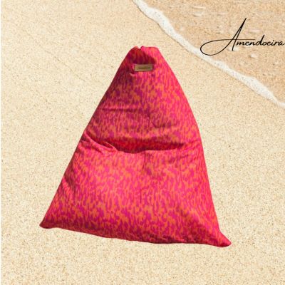 Pufe triangular rosa com padrão abstrato colocado na areia da praia