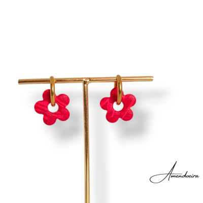 Brincos dourados com flores vermelhas penduradas em suporte dourado