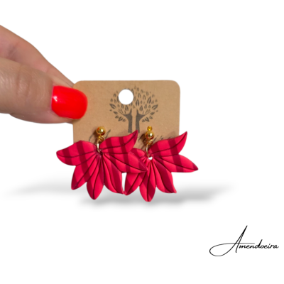 Brincos vermelhos em forma de folhas com detalhes dourados em cartão castanho