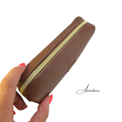 Estojo castanho em pele sintética com fecho dourado segurado por mão