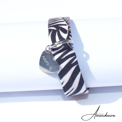 Pulseira de tecido preta e branca com padrão zebra e pendente de coração metálico gravado
