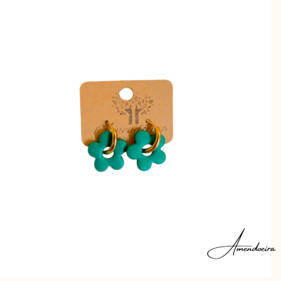 Brincos com flor verde e argola dourada em cartão castanho com desenho de árvore.