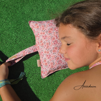 Almofada estampada floral rosa usada por criança a dormir sobre relva artificial verde
