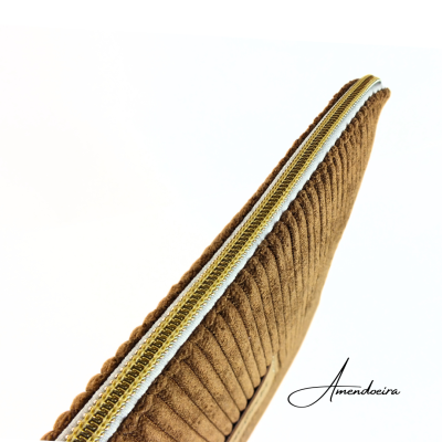 Detalhe de almofada castanha canelada com fecho dourado e fita branca