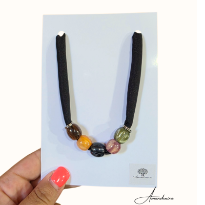 Colar com cordão preto e contas coloridas num cartão branco Amendoeira.