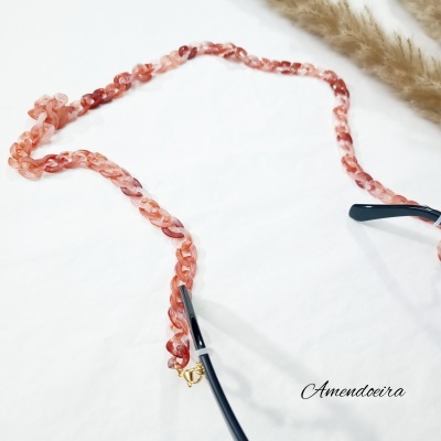 Corrente vermelha e rosa para óculos com fecho dourado sobre fundo branco