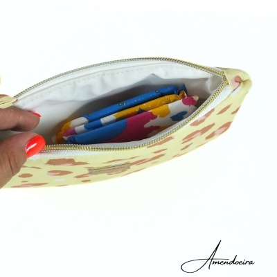 Necessaire amarela com padrão castanho aberta contendo lenços coloridos