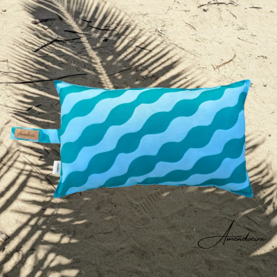 Almofada azul com padrão de ondas sobre areia com sombra