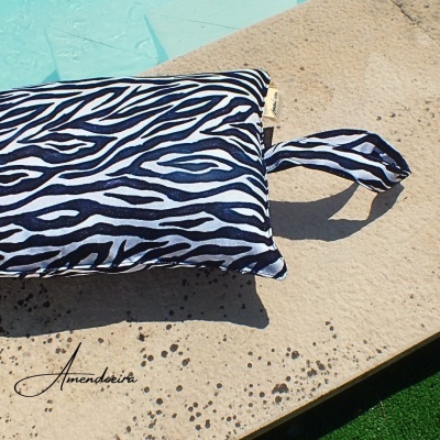 Almofada azul e branca com padrão de zebra numa superfície clara texturada