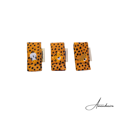 Três presilhas de tecido laranja com pintas pretas e rostos de animais estilizados