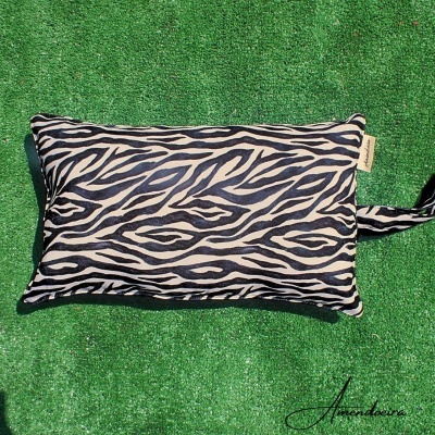 Travesseiro rectangular bege e preto com padrão de riscas sobre relvado verde