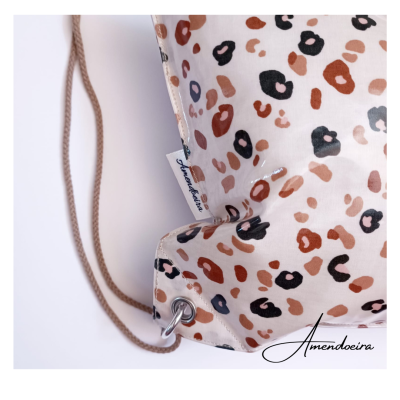 Mochila com padrão animal print em tons castanho, cordões marrons e etiqueta Amendoeira