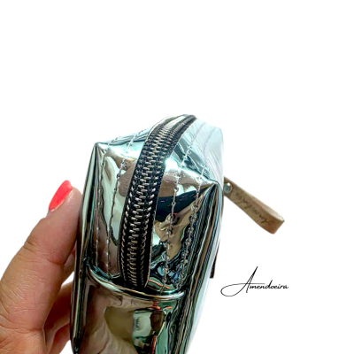 Necessaire prateada brilhante com fecho de correr segurada por mão
