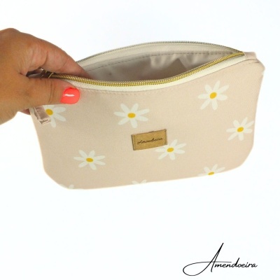 Mala bege com margaridas e fecho dourado, etiqueta 'Amendoeira'
