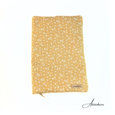 Capa tecido amarelo com pequenas flores brancas e etiqueta Amendoeira