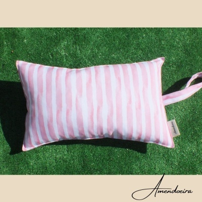Almofada riscada em branco e rosa sobre relva sintética verde