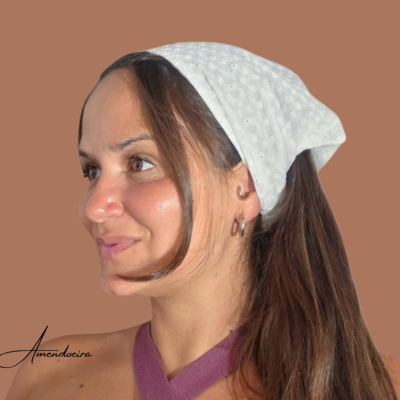 Mulher com lenço branco de padrão texturizado na cabeça e fundo castanho.